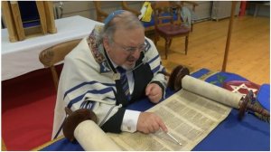 A Jew reading a Torah scroll with a pointer. A Jew, out of respect would not touch the scroll directly.